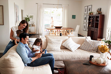 Young Hispanic family sitting on sofa reading a book together in their living room